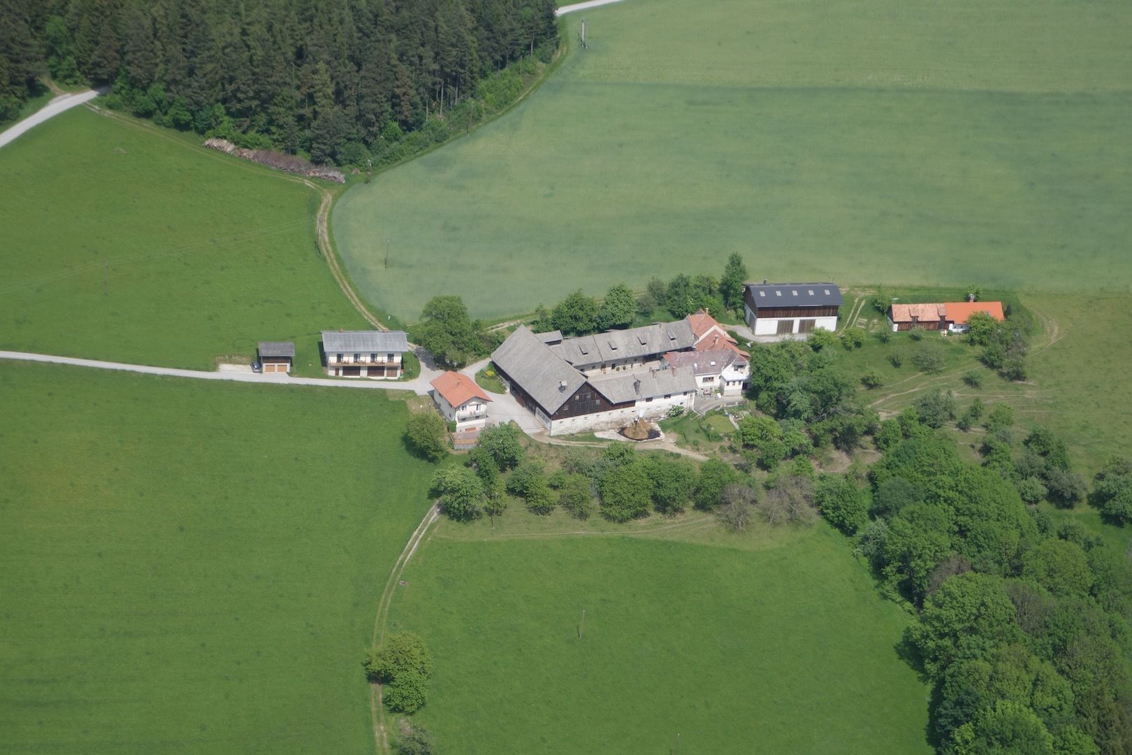 Aerial view of a farm surrounded by green fields and forests.
