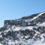 Winter landscape with the Ottohaus on a snow-covered mountain under a clear sky.