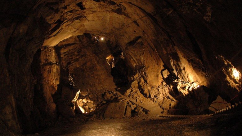 Interior view of an illuminated cave with stony walls and a narrow path.