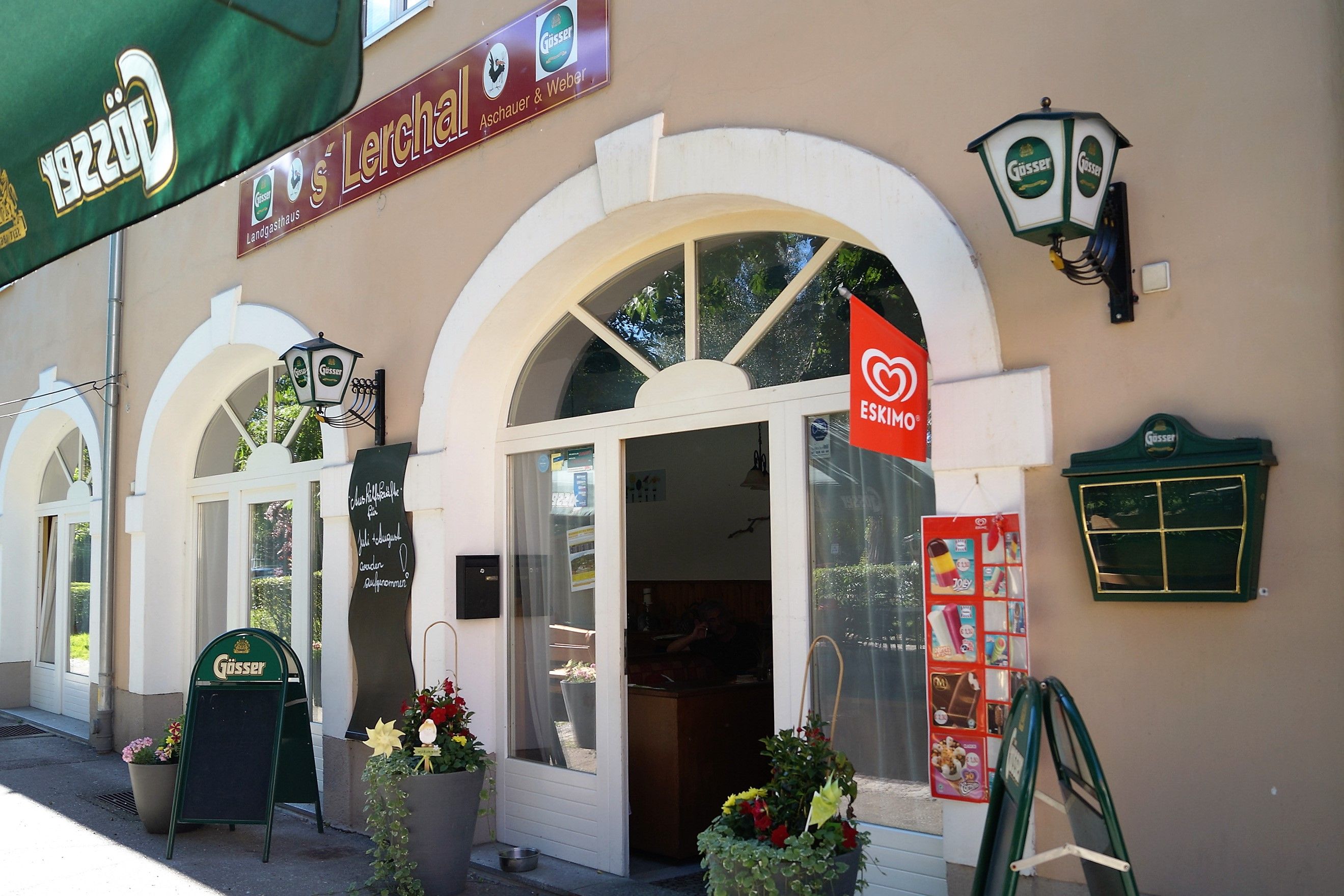 Exterior view of a restaurant with Gösser signs and Eskimo ice cream advertising.
