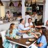 Table with visitors who are eating. Behind it the Baar with many drinks.
