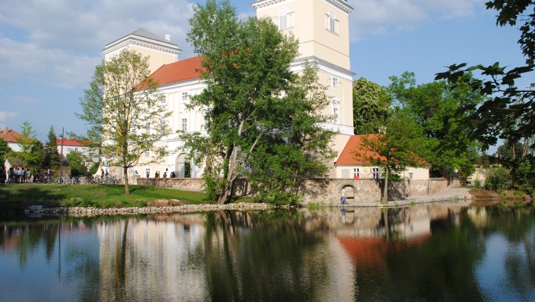 Wolkersdorf Castle with reflection in the water and surrounded by trees.