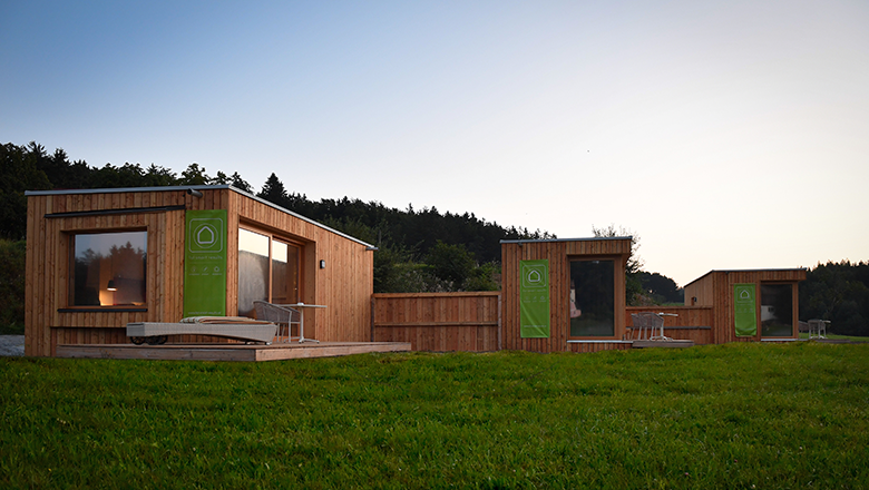 Modern wooden huts on a meadow at sunset.