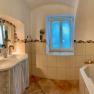 A bathroom with double washbasin, bathtub and tiled floor.