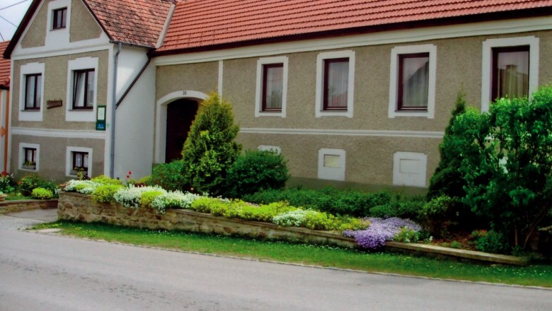 Traditional farmhouse with well-kept garden and red tiled roofs.
