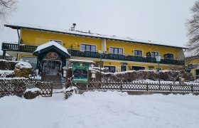 Yellow building in the snow with green veranda and entrance.