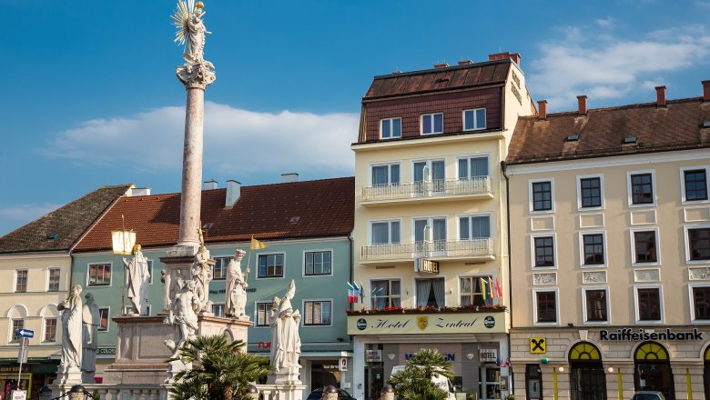 The Hotel Zentral directly on the main square, © Hotel Zentral A square with a column and statues, surrounded by buildings, including the Hotel Zentral.