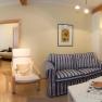Panorama of a cozy living room with sofa, dining table and bedroom in the background.