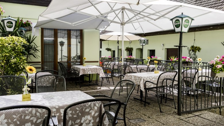 Comfortable terrace with tables, chairs and parasols, decorated with flowers.