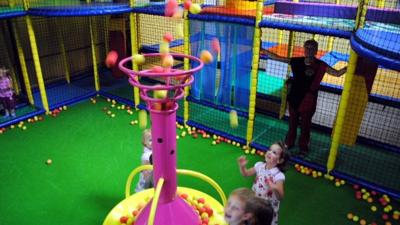 Children playing in an indoor playground with a ball fountain.
