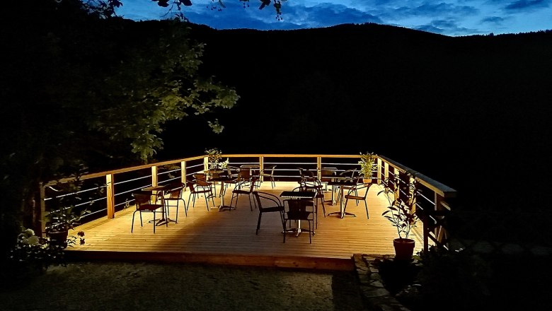 Illuminated terrace with chairs and tables at night.