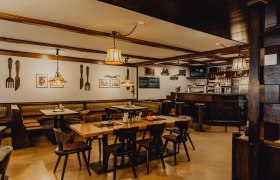 Cozy pub with wooden furniture, bar and decorative lamps.