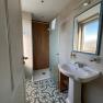 Modern bathroom with patterned tiled floor, washbasin, mirror and shower with glass wall.