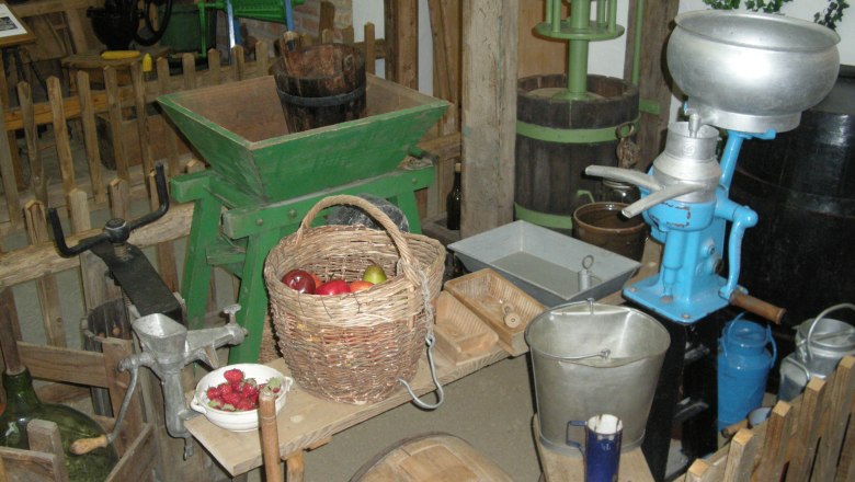 Old agricultural tools and a basket of fruit in a museum.