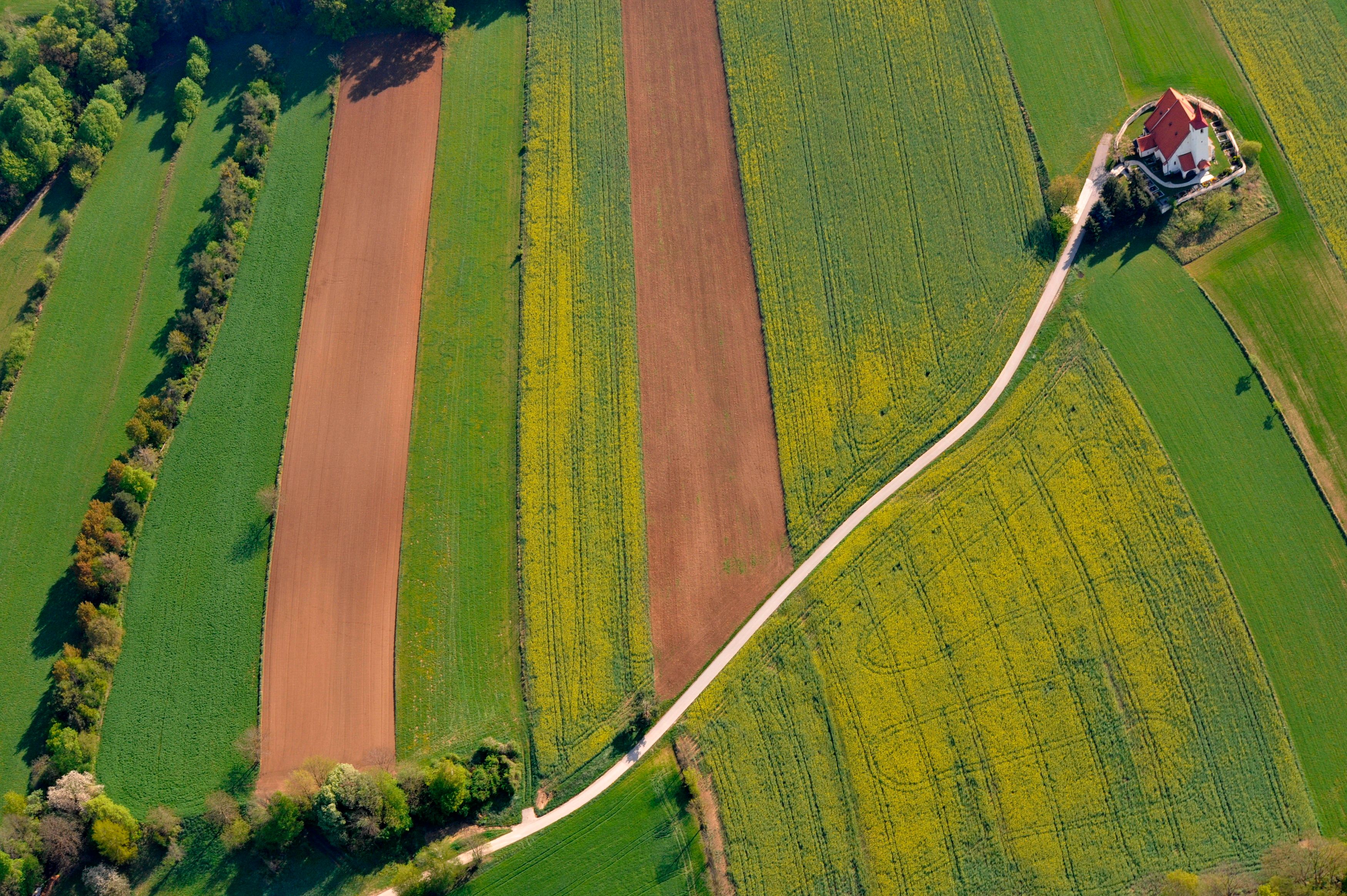 Aerial view of fields with a church on the edge.