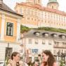 Two women enjoy ice cream sundaes in the garden with a view of Melk Abbey.