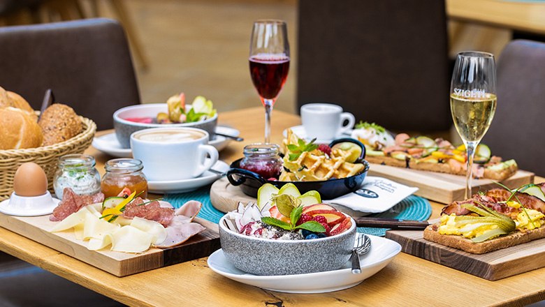 Breakfast table with various dishes, champagne glasses and coffee.