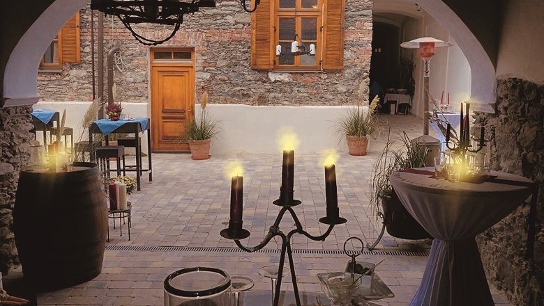 Cozy inner courtyard of a caf&eacute; with candlelight and rustic stone wall.