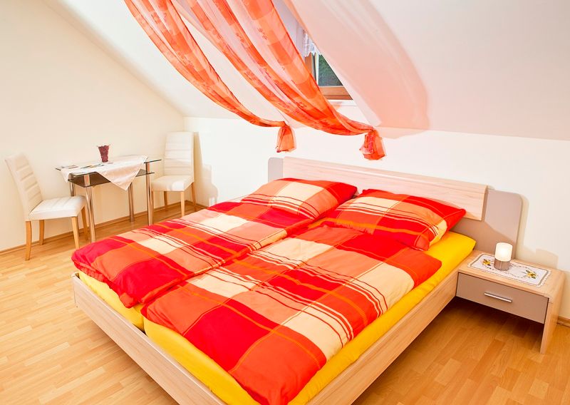 Bright bedroom with red comforter cover and decorative curtains.