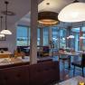 Interior view of a modern hotel restaurant with wooden furniture and large windows.
