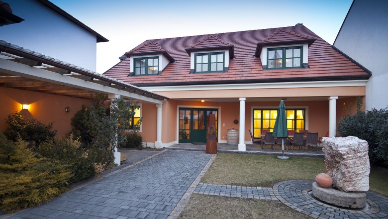 Guest house with red roof and garden in the foreground.