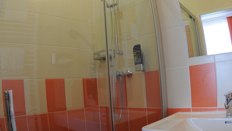 Bathroom with shower, washbasin and orange and white tiles.