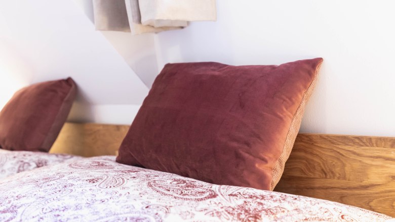 Close-up of a bed with red pillows and patterned bed linen.