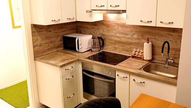 Modern kitchen with wooden worktop, white cupboards, microwave, stove and sink.