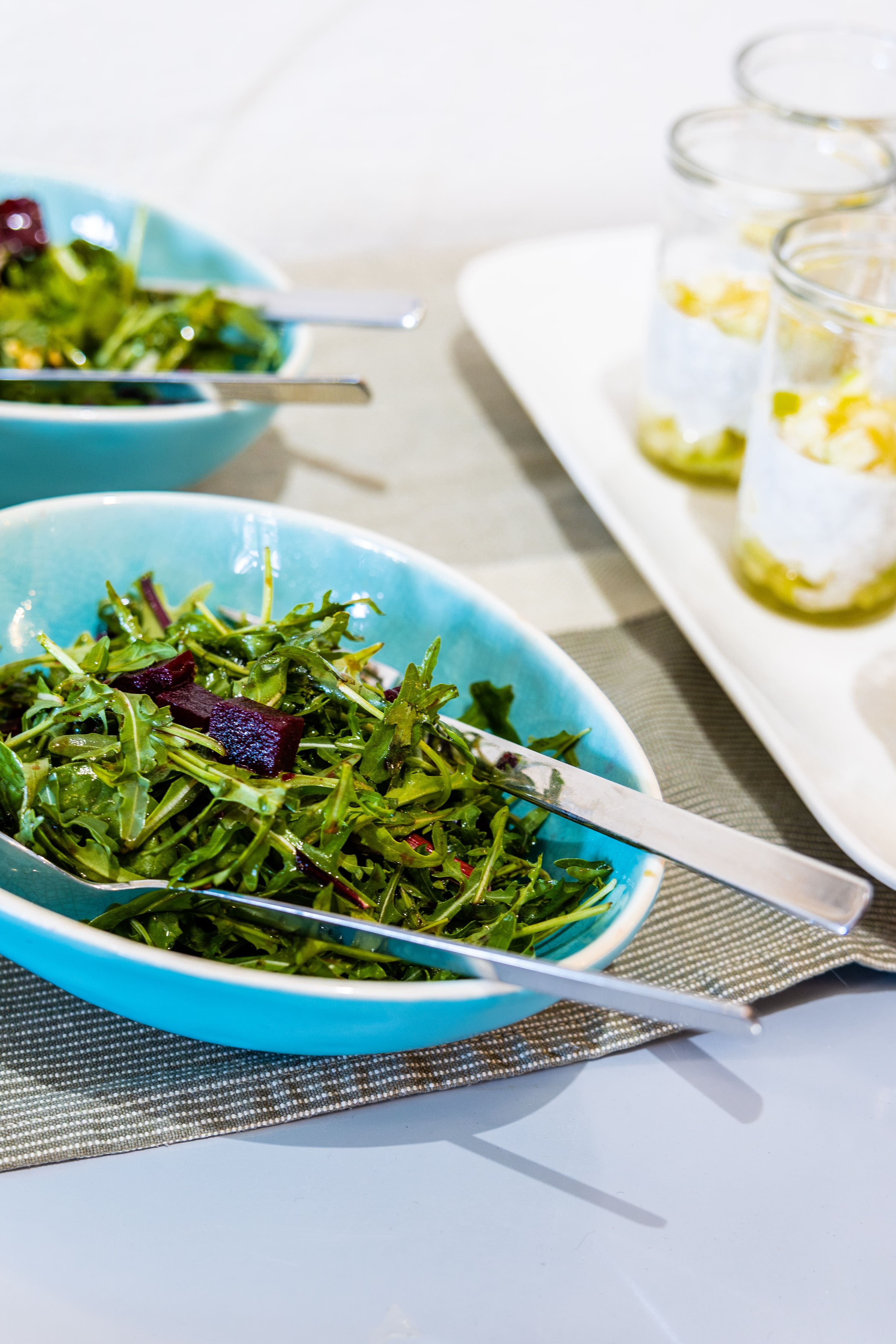 Bowl with rocket salad and cutlery on a table.