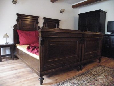 Wooden bed in rustic bedroom with red bed linen.