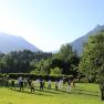 Group of people doing Tai Chi in a meadow against a mountain backdrop.