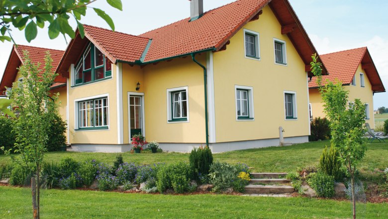 Yellow detached house with red roof and well-kept garden.