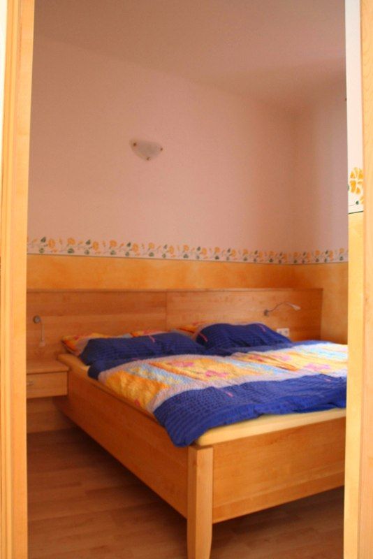 Bedroom with wooden bed and colorful bedding.