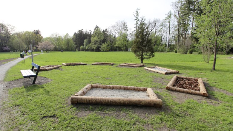 A city park with a barefoot path made of various materials and a park bench.