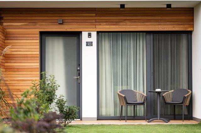 Modern terrace with two chairs and a table in front of a guest house.
