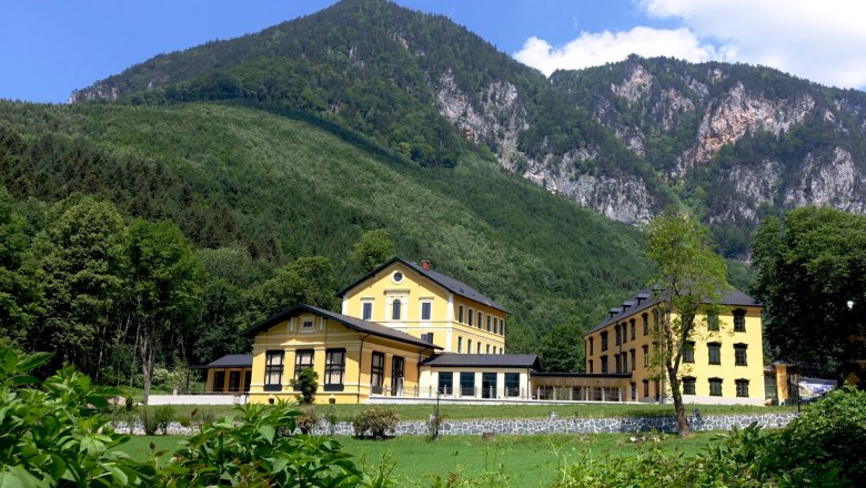 Yellow building in front of a wooded mountain in Reichenau.