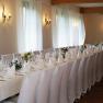 Elegant function room with long, festively laid tables and white chairs.