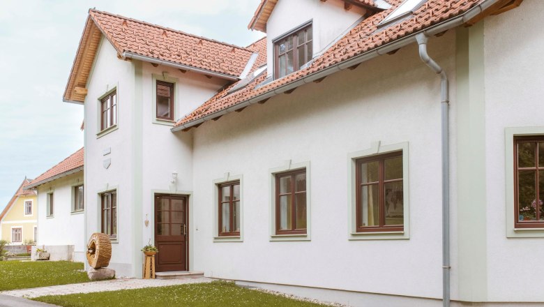 Exterior view of a house with red tiled roofs and white walls.