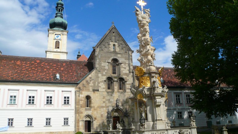 Inner courtyard of Heiligenkreuz Abbey with baroque column and church tower.