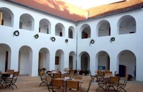 Inner courtyard of the Eisenhuthaus with arcades and wooden furniture.