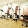 A fitness room with treadmill, exercise bike and strength equipment on a wooden floor.