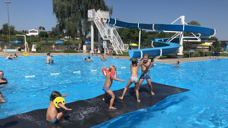 Children play on a floating mat in front of a water slide at the Neuhofen an der Ybbs outdoor pool.
