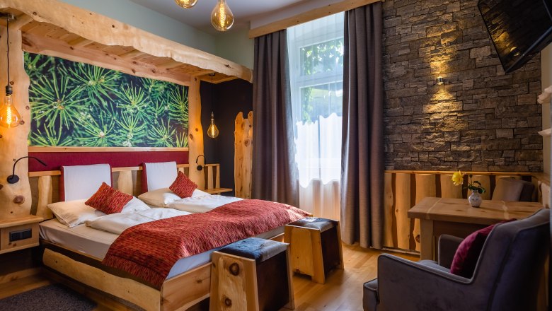 Cozy hotel room with wooden furniture, stone wall and large window.
