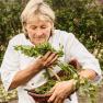 Person in the garden with fresh herbs in a basket.