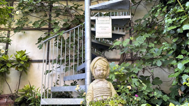 Stone steps in the garden with plants and a statue of a child.