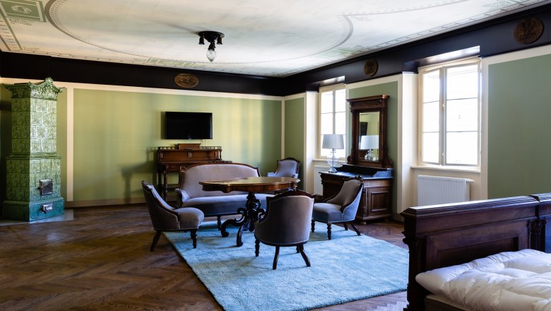 Elegant room with antique furniture, green tiled stove and carpet.