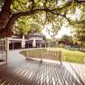 A garden with a terrace, trees and a pavilion in the sunlight.