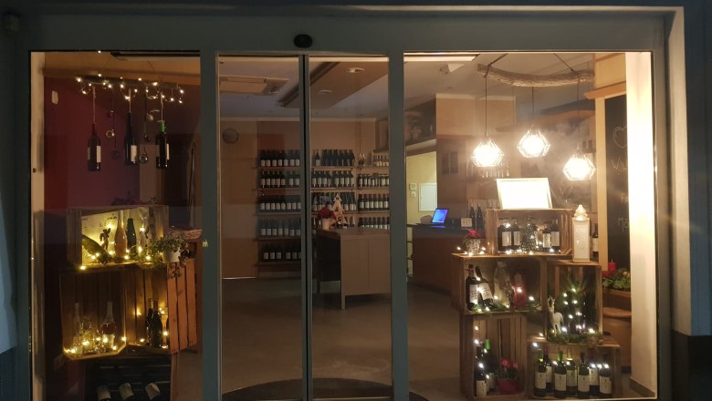 Wine store at night with illuminated shop window and wine bottles.
