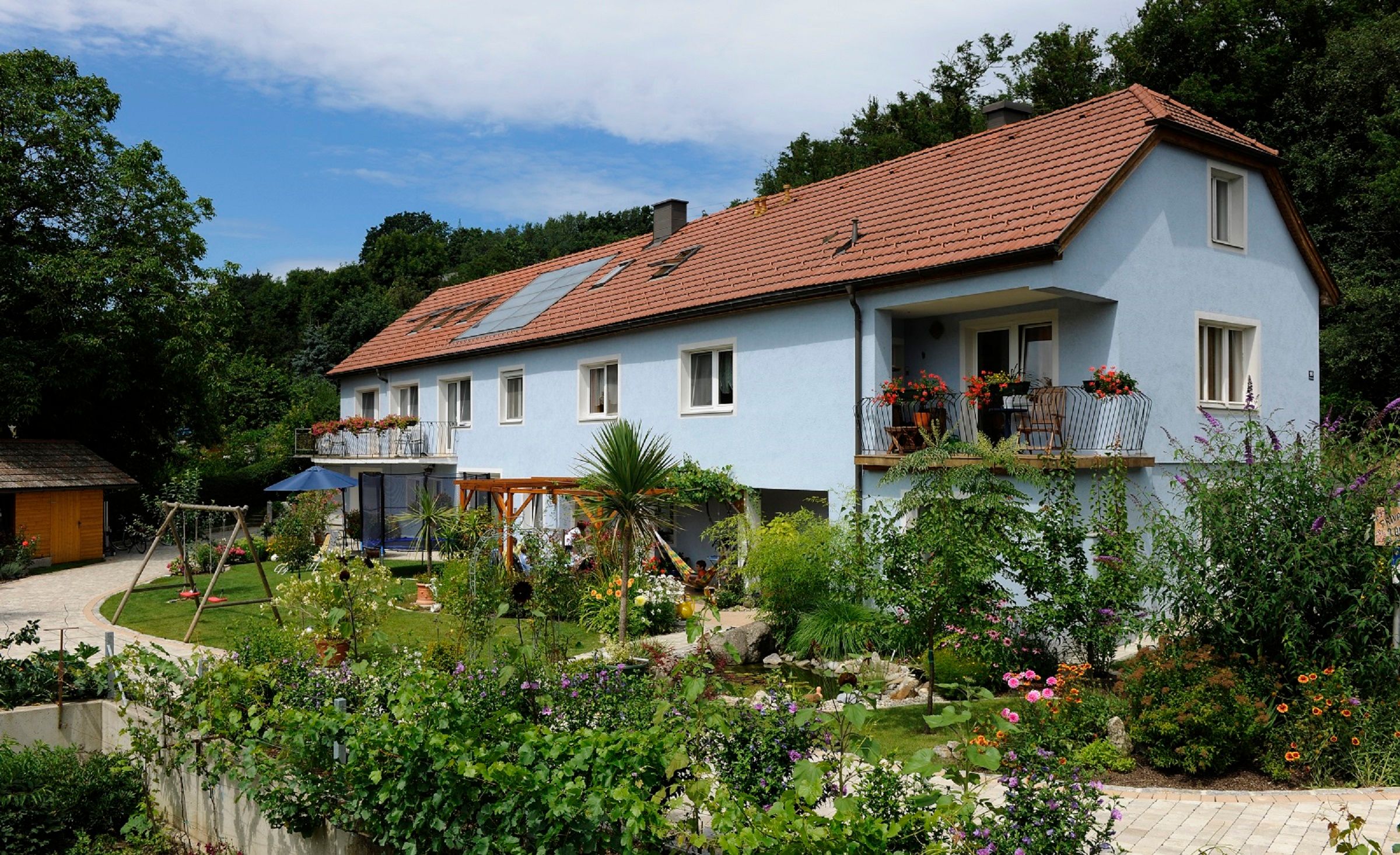 Exterior view of a blue guest house with garden and playground.