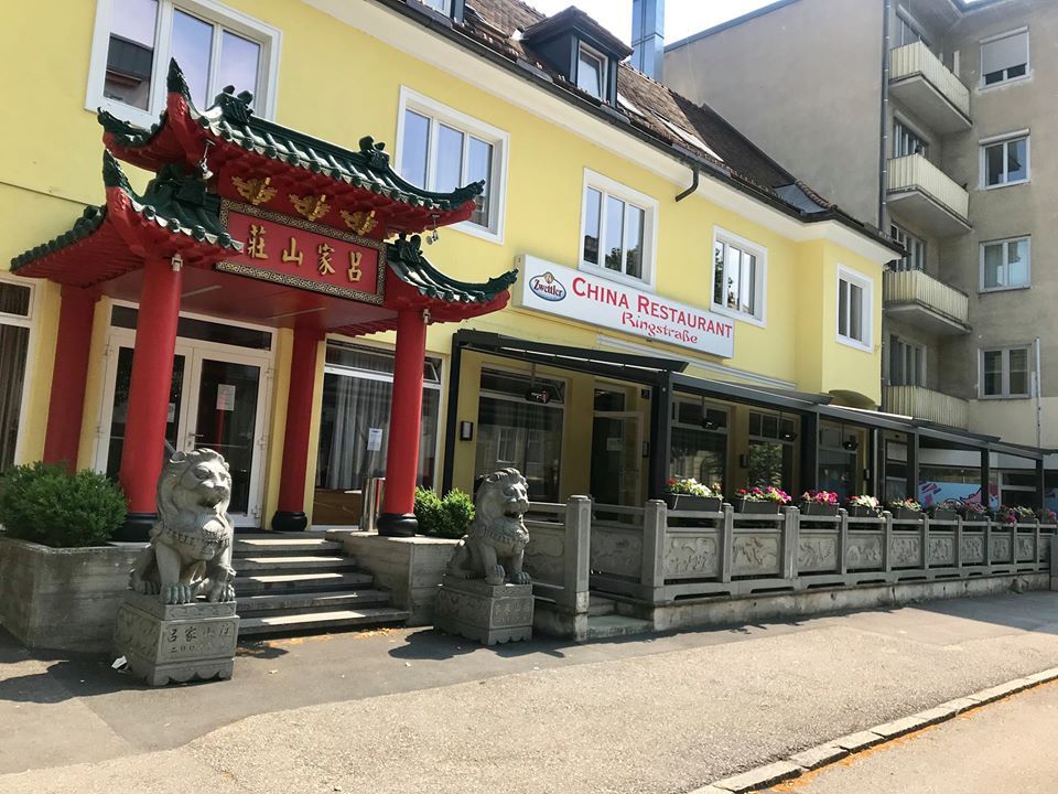 Exterior view of a Chinese restaurant with traditional gate and lion statues.